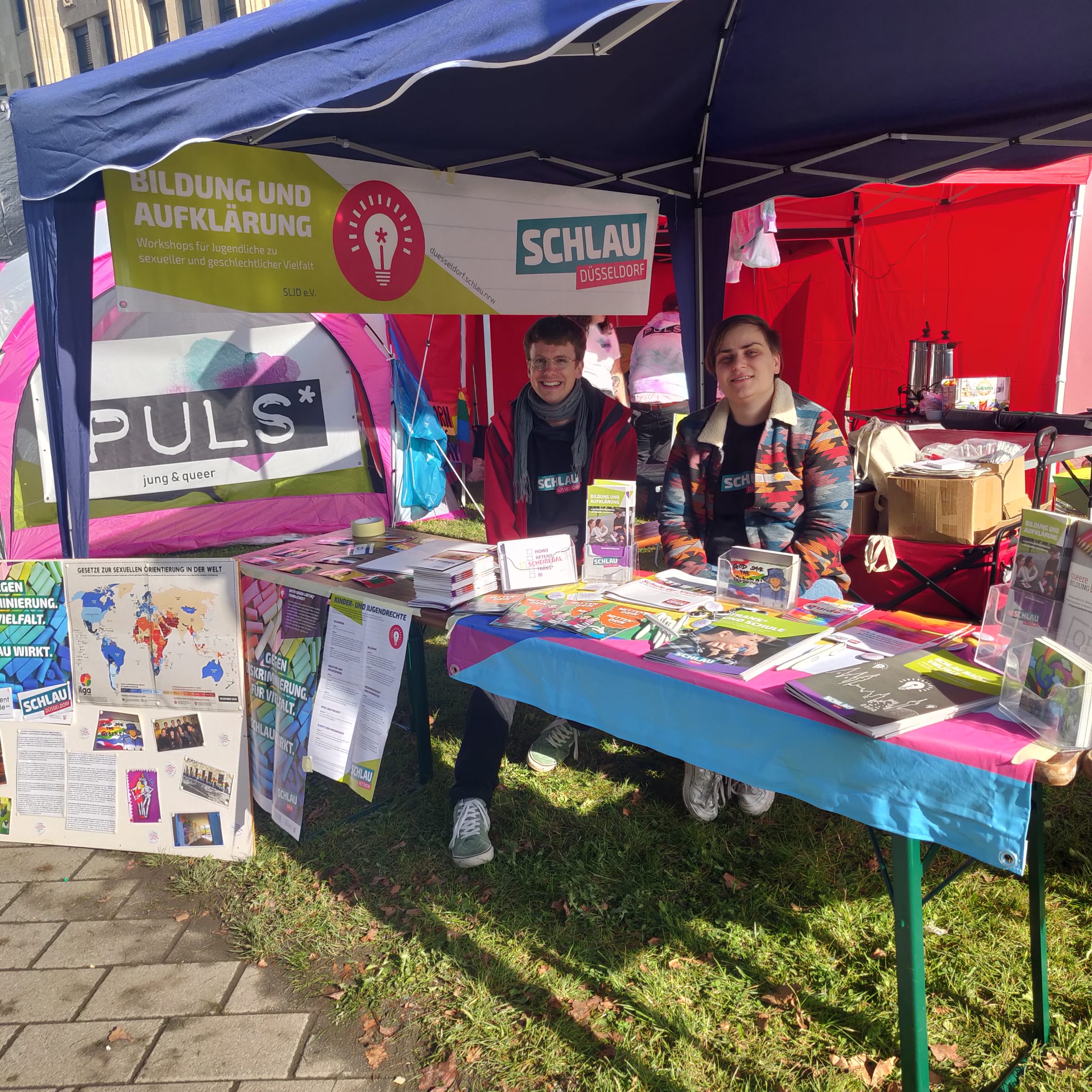 Ein geschmückter Stand von SCHLAU mit vielen Flyern und Bannern.